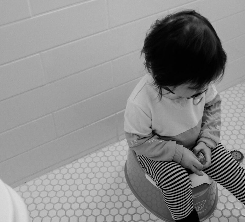 grayscale photo of child in white long sleeve shirt sitting on floor